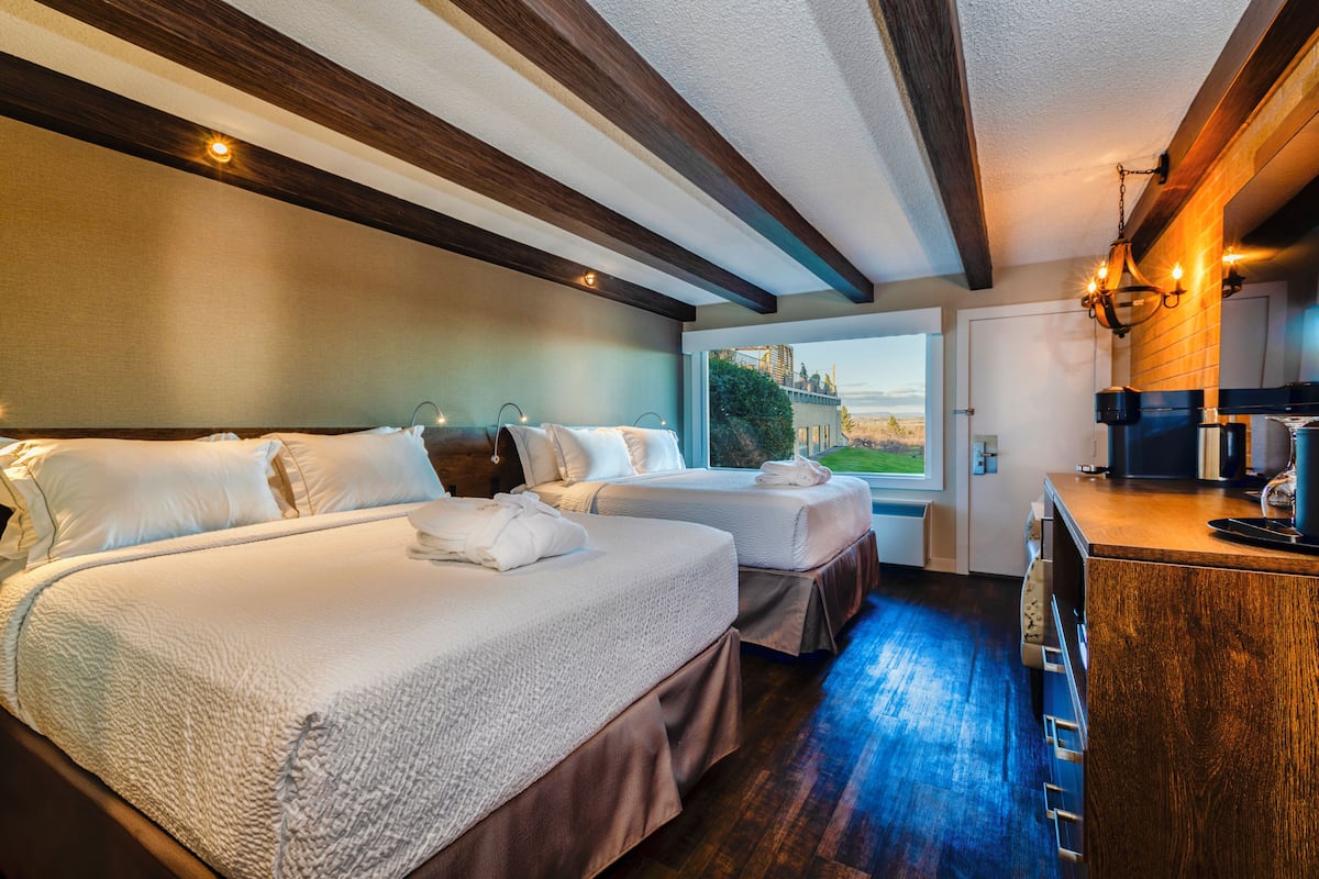 Habitación de hotel con dos camas, techo de madera, vistas al exterior y una kitchenette.