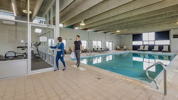 Een binnenzwembad, ligstoelen bij het zwembad