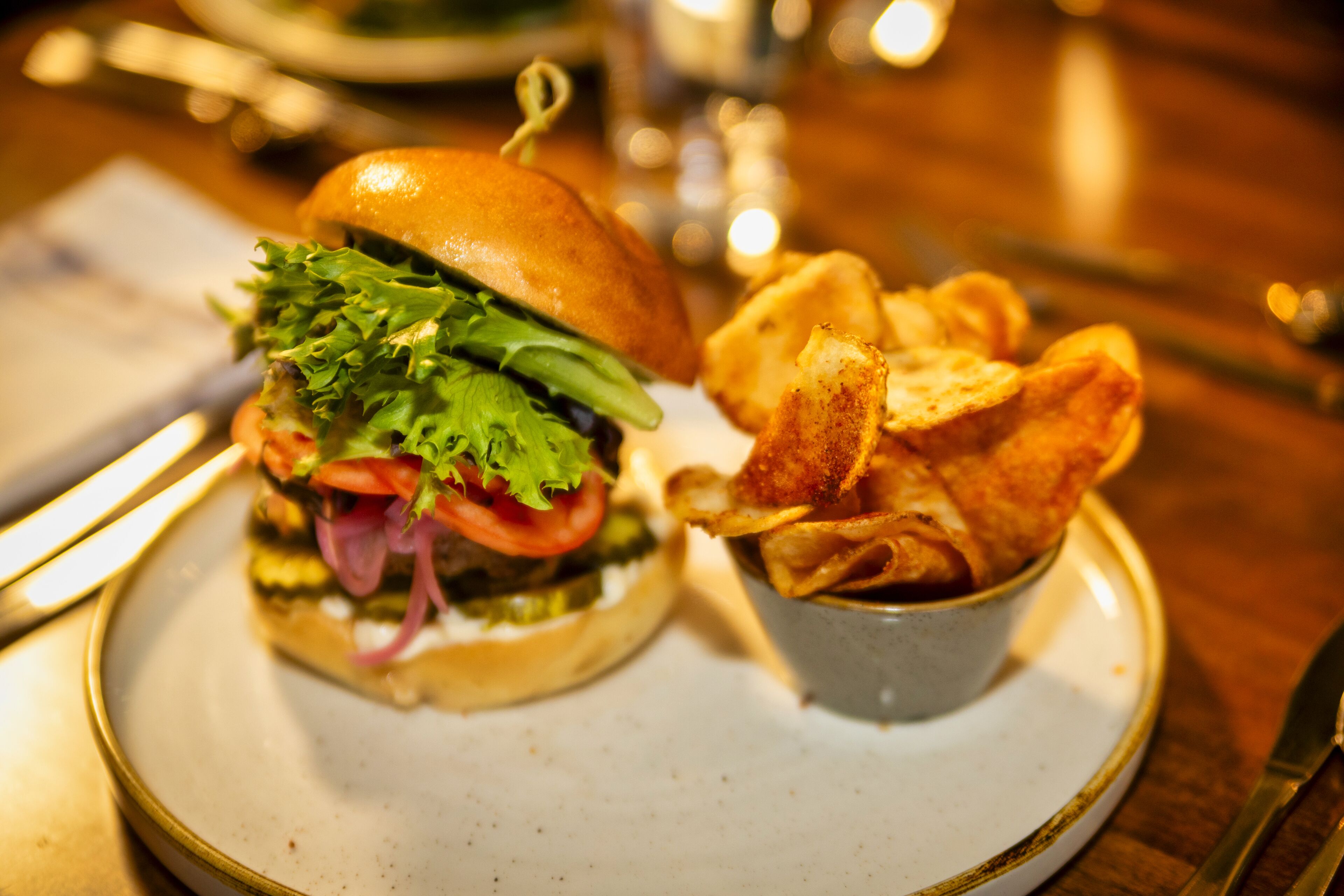 A plate with a sandwich and a small bowl of chips.