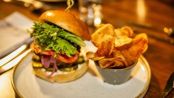 A plate with a sandwich and a small bowl of chips.