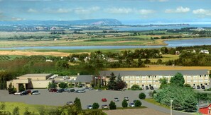 A building with a parking lot and a view of a lake and mountains.