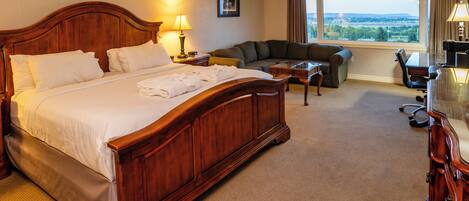 A hotel room with a large bed, a sofa, a desk, and a view of the outdoors.
