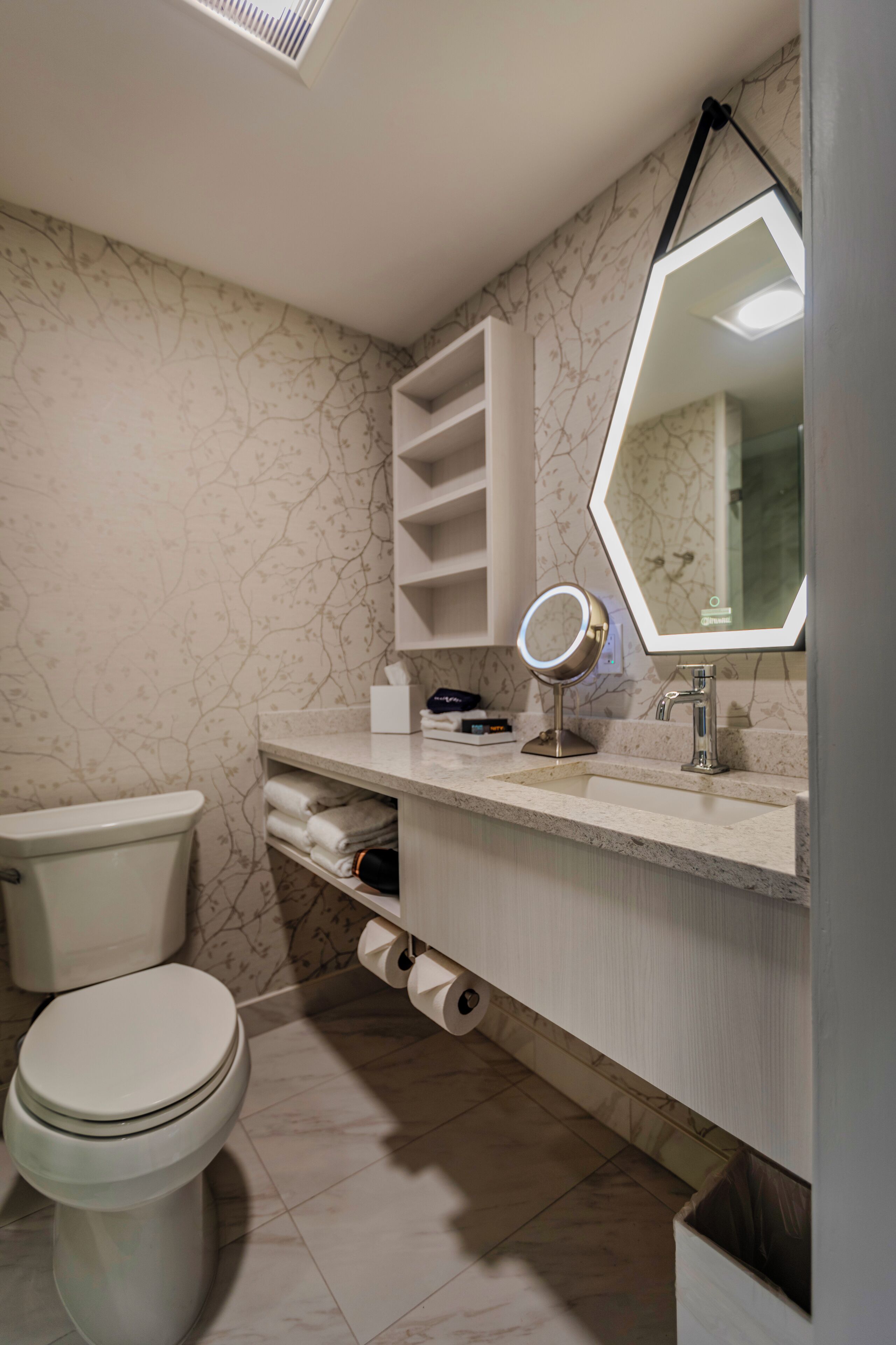 Un baño moderno con inodoro, lavamanos y espejo.