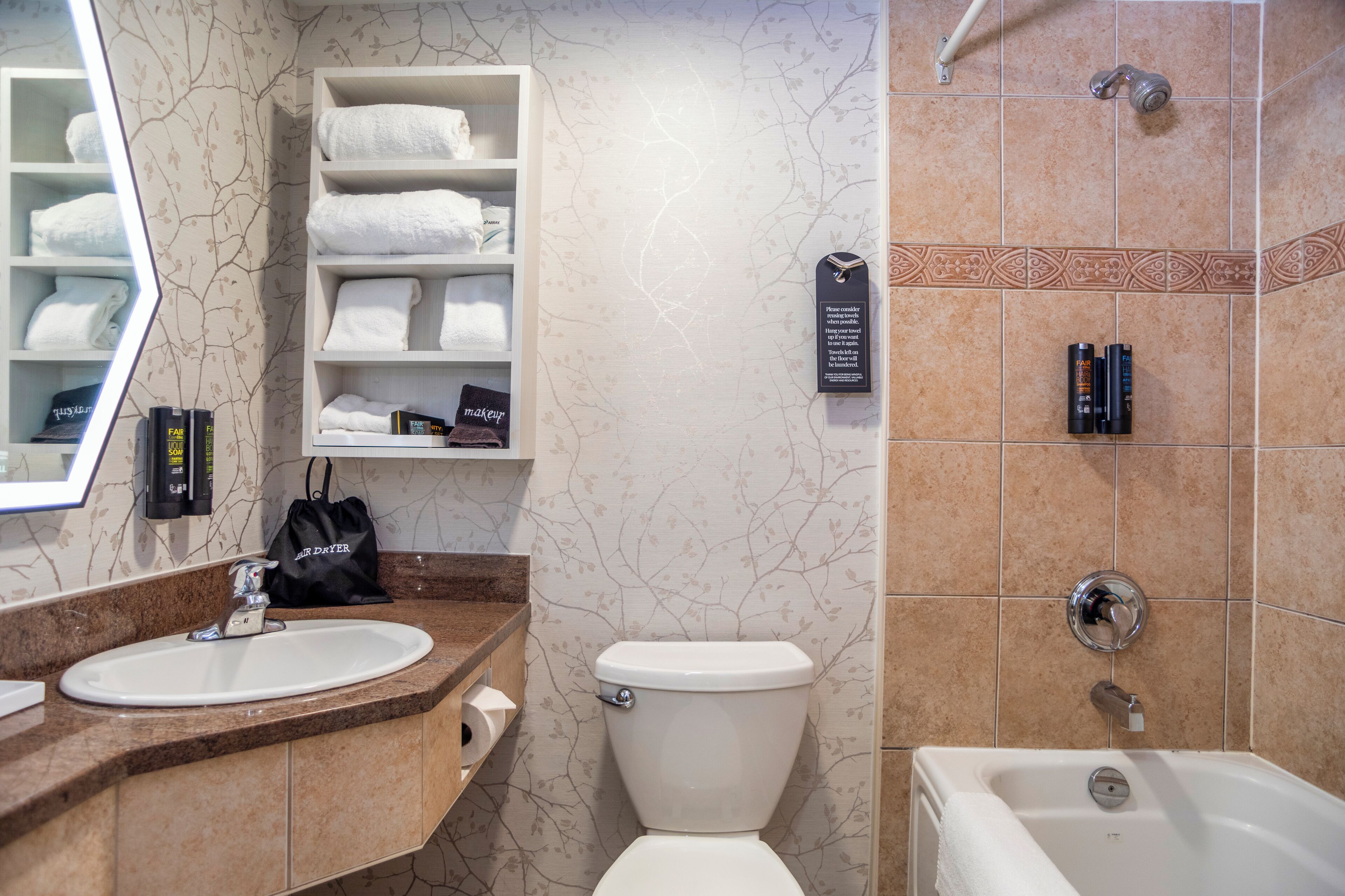 A bathroom with a sink, toilet, and bathtub. There are shelves with towels and toiletries.