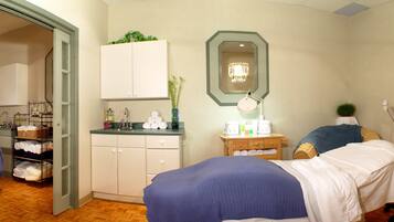 A hotel room with a bed, a desk, a chair, a mirror, and a small cabinet.