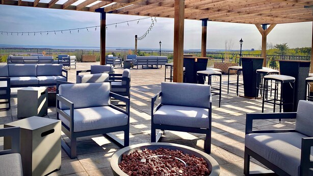 An outdoor patio with wooden pergola, seating, and a view of the landscape.