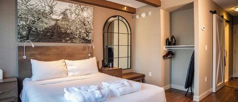 Una habitación de hotel con una cama grande, un cabecero de madera, un espejo y un armario.