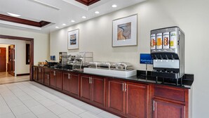 A hotel reception area with a juice bar, framed artwork on the wall, and a buffet setup. - Best Western Garden Inn (Bentleyville)