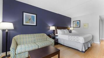Una habitación de hotel con sofá, cama, mesita de noche y dos lámparas.