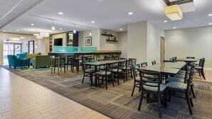 A spacious dining area with multiple tables and chairs, a reception desk, and a counter. - Best Western Garden Inn (Bentleyville)