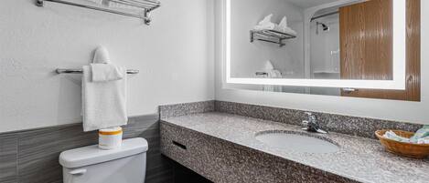 A bathroom with a toilet, a sink, a mirror, and a towel rack.