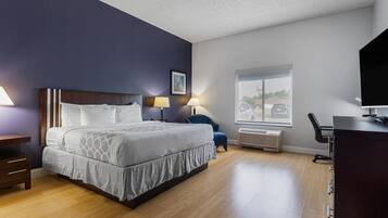 A modern hotel room with a large bed, bedside tables, a desk, and a window with a view of the outside.
