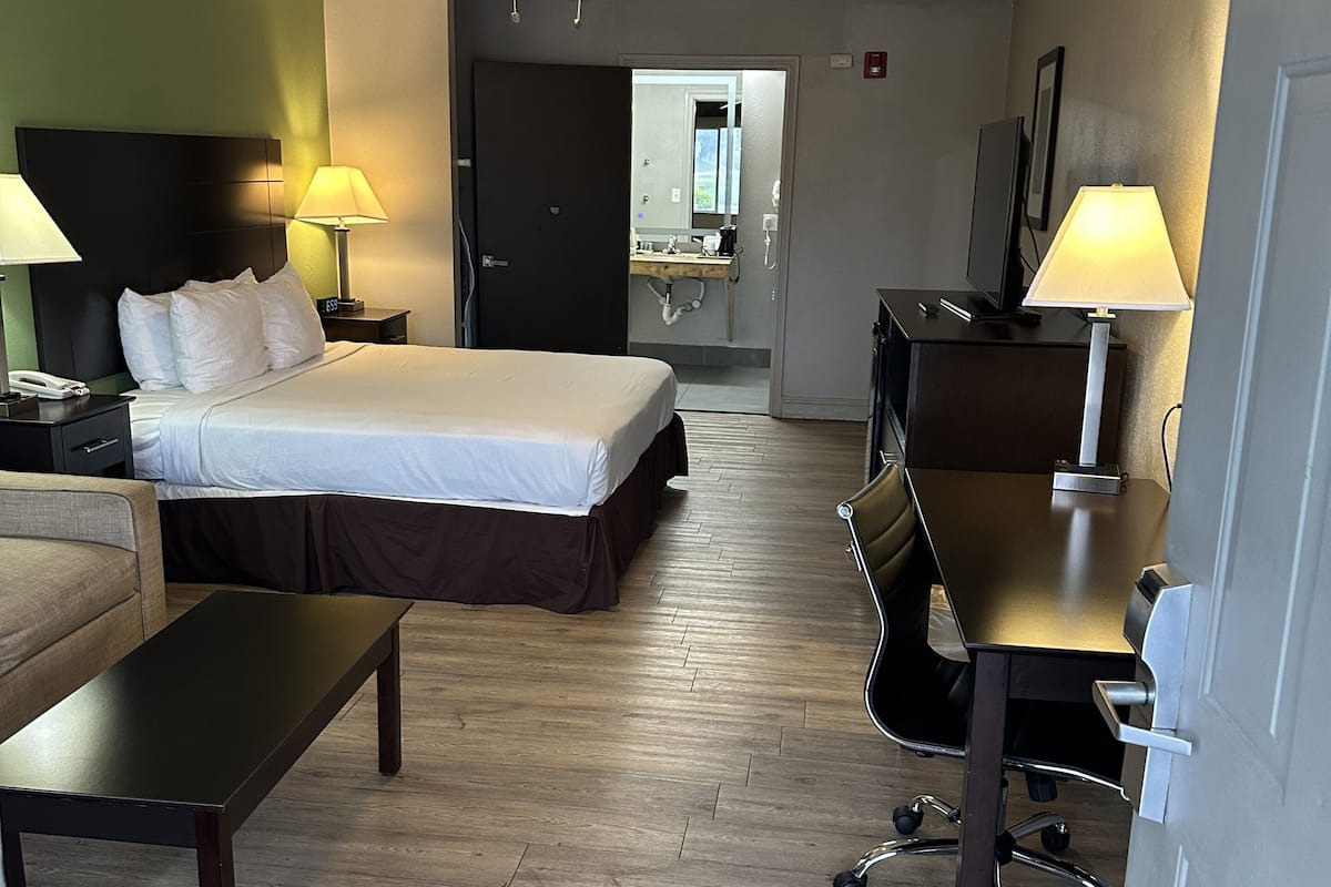 A hotel room with a bed, desk, chair, and a ceiling fan.