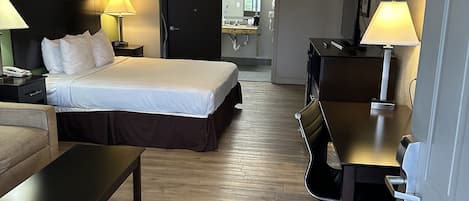 A hotel room with a bed, desk, chair, and a ceiling fan.