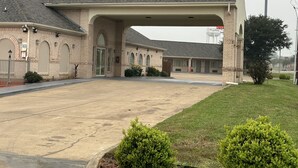A Bestway Inn with a covered parking area and a brick facade. - Bestway Inn (Kaufman)