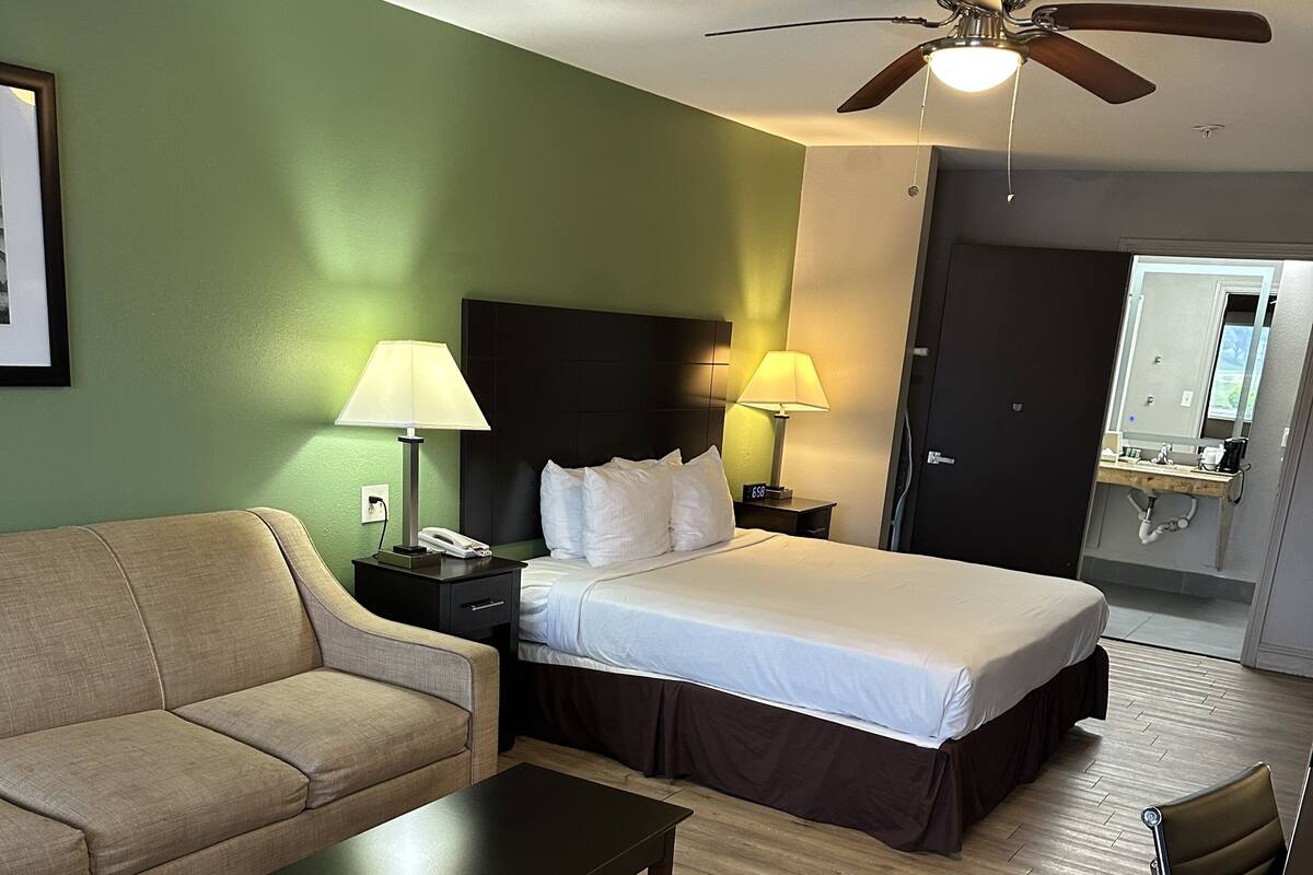 A hotel room with a bed, a sofa, a coffee table, a desk, and a chair.