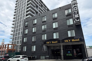 A hotel building with a modern facade, multiple balconies, and a prominent entrance with signage. - Prince Flushing Hotel (Flushing)