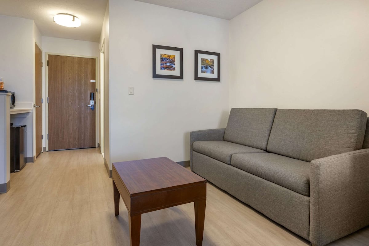 A living room with a grey sofa, a wooden coffee table, and two framed pictures on the wall.