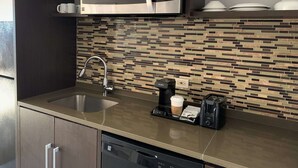A modern kitchen with a stainless steel sink, a coffee maker, a toaster, and a microwave.