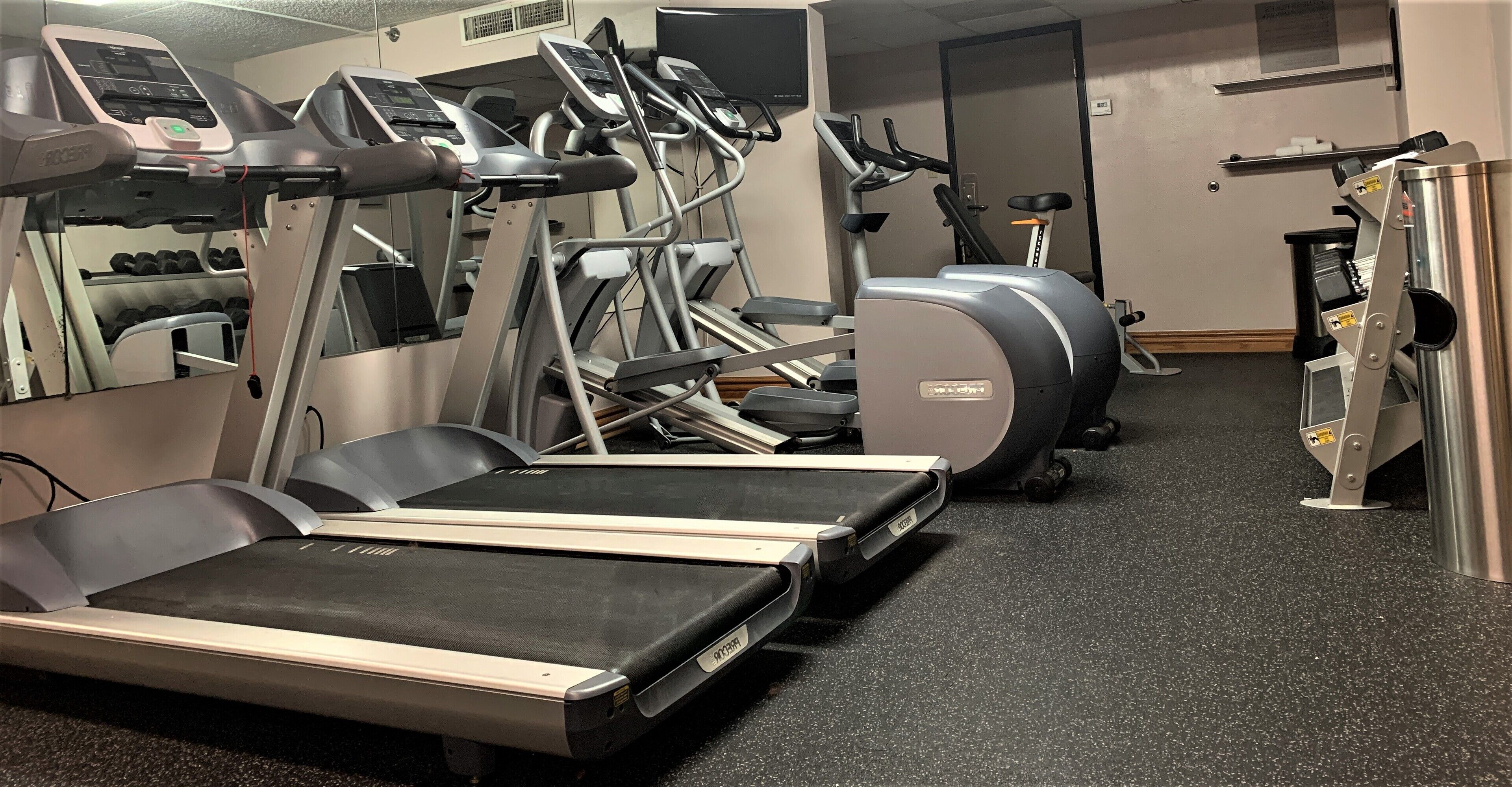 A gym with treadmills, elliptical machines, and weight equipment.