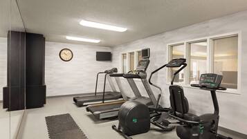 Ein Fitnessraum mit Laufbändern, Crosstrainern und Ergometer, ausgestattet mit einem digitalen Display.