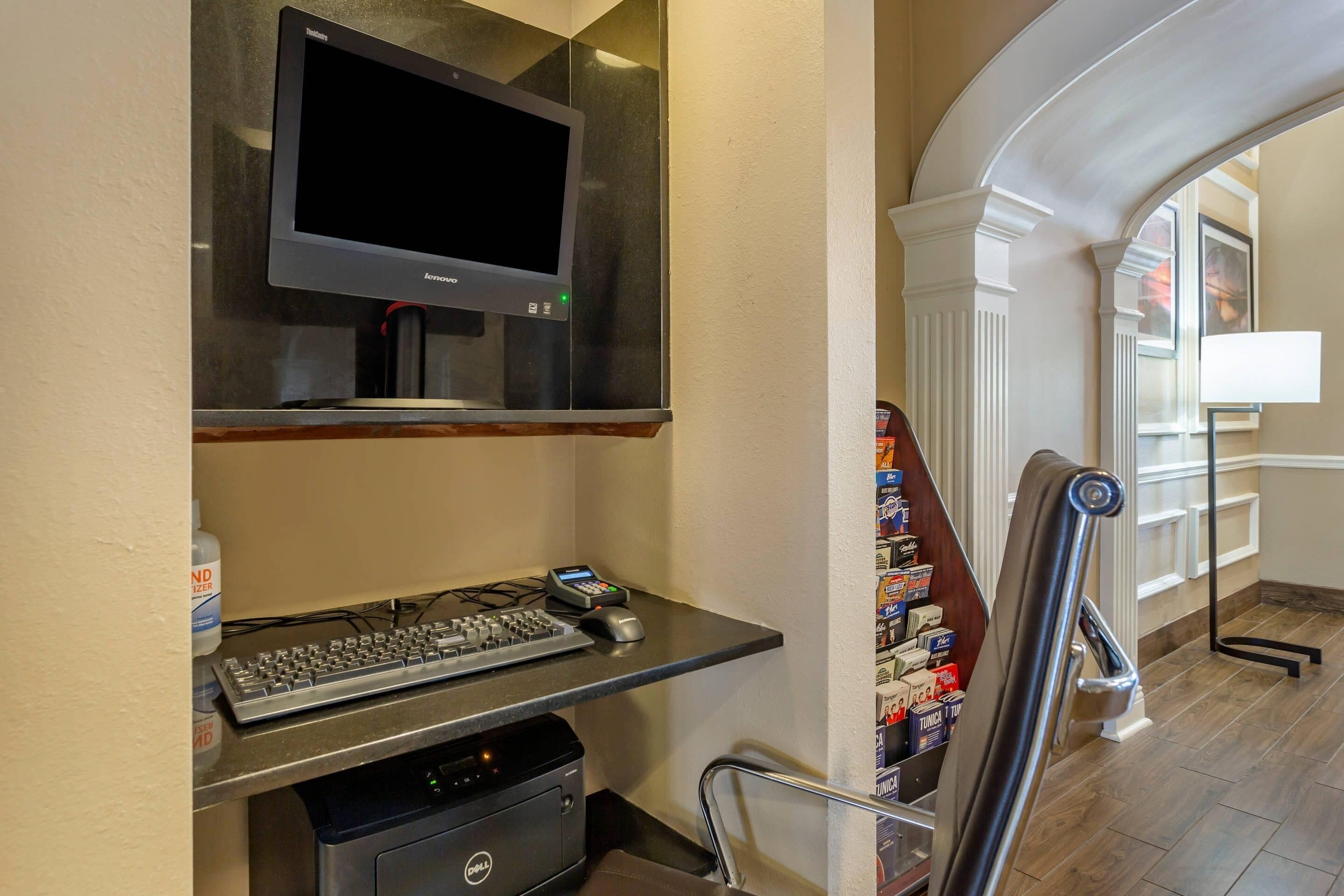 Habitación de hotel con escritorio, televisor de pantalla plana, teclado, ratón, impresora y una silla.