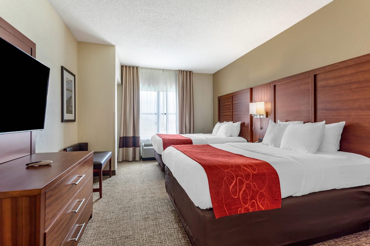 A hotel room with two beds, a TV, a desk, and a chair.