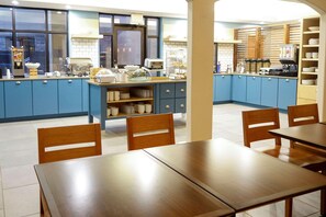 A modern kitchen with blue cabinets, a central island with a coffee machine, and a breakfast bar. - Country Inn & Suites by Radisson, Houston Northwest, TX (Houston)