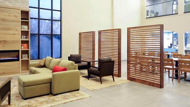 A modern living room with a sectional sofa, a fireplace, wooden partitions, and a dining area with tables and chairs.