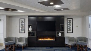 A modern room with a fireplace, two armchairs, and a large flat-screen TV. - Holiday Inn Express & Suites Winner by IHG (Winner)