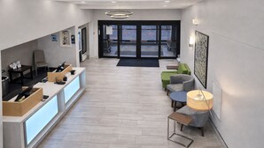 A reception area with a counter, seating, and a view of the entrance. - Holiday Inn Express & Suites Winner by IHG (Winner)