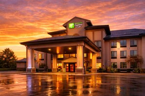A Holiday Inn Express & Suites hotel with a covered entrance, columns, and a parking lot.