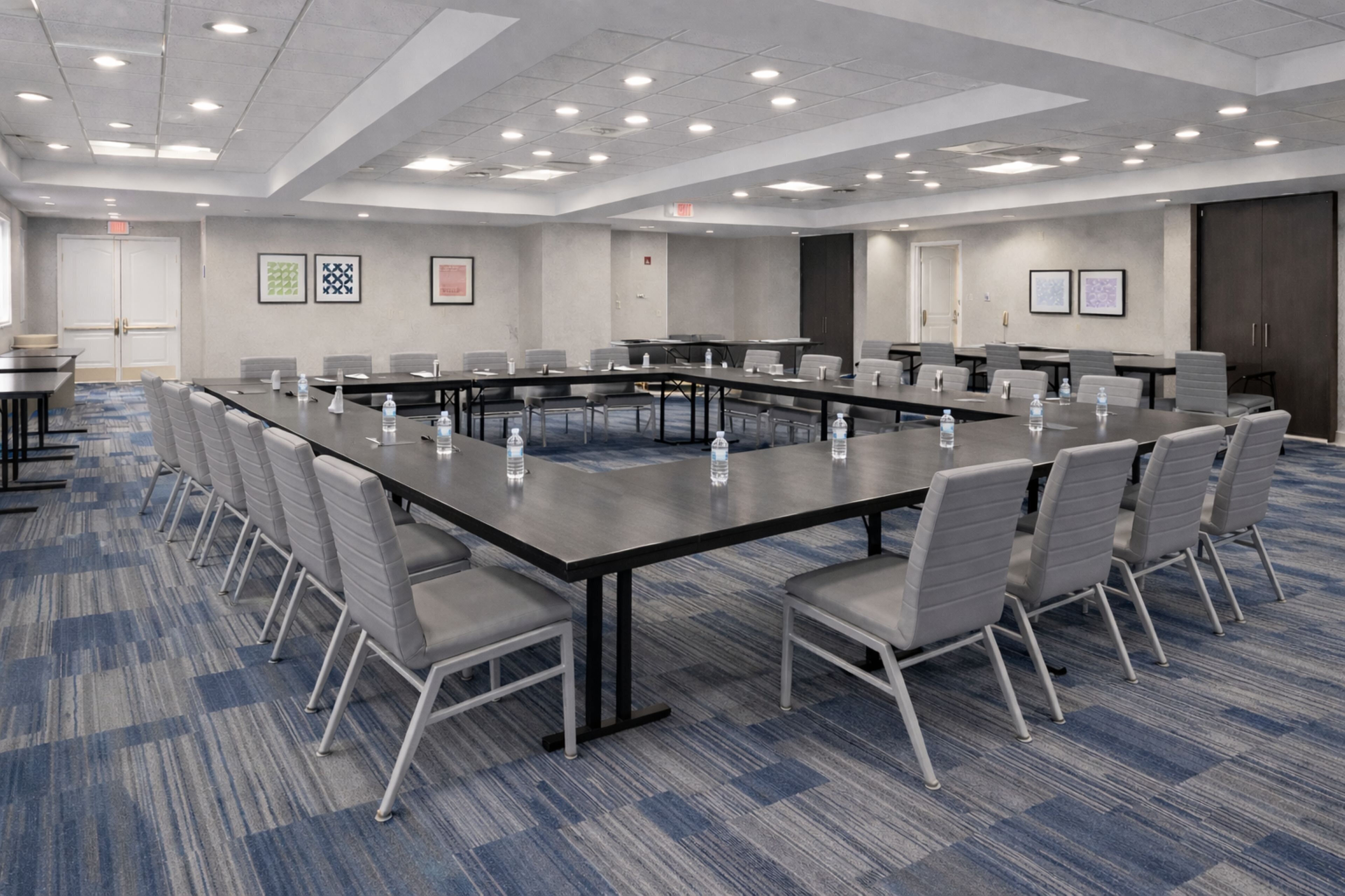 Un salón de conferencias con una larga mesa, sillas y botellas de agua.