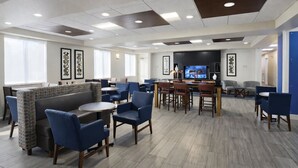 A modern dining area with booths, round tables, and blue chairs. - Holiday Inn Express & Suites Winner by IHG (Winner)