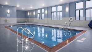An indoor swimming pool with clear water, metal ladders, and a tiled floor. - Holiday Inn Express & Suites Winner by IHG (Winner)