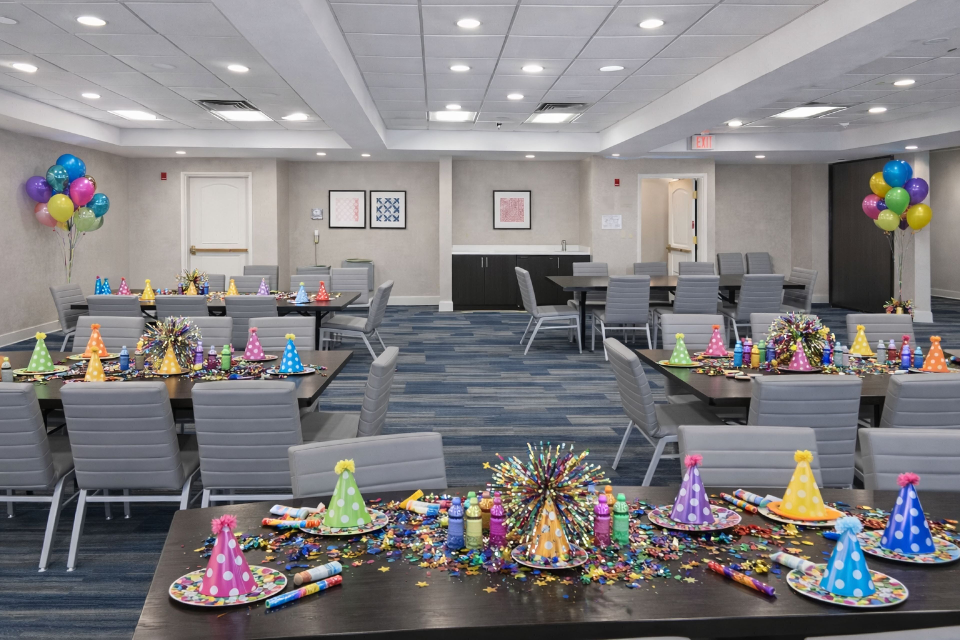 A conference room with tables set for a party, featuring party hats and balloons.