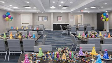 A conference room with tables set for a party, featuring party hats and balloons.