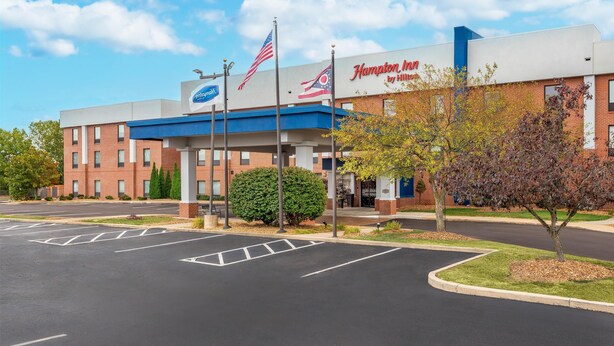 A Hampton Inn by Hilton hotel with a parking lot and a clear sky.