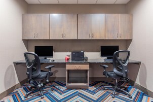 Un espacio de trabajo con dos escritorios, dos sillas, una impresora y un mueble bajo.