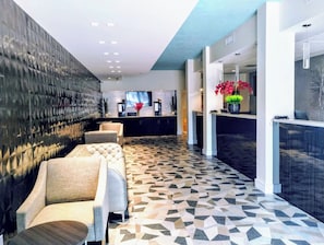A modern lobby with a patterned floor, seating area, reception desk, and a large wall-mounted TV. - Red Carpet Inn Airport and Cruise Port Hotel Fort Lauderdale (Fort Lauderdale)
