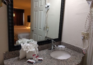 A hotel bathroom with a granite countertop, a white sink, a hairdryer, and a mirror. - Red Carpet Inn Airport and Cruise Port Hotel Fort Lauderdale (Fort Lauderdale)