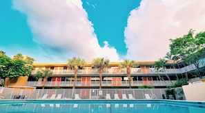 A hotel with multiple balconies, a swimming pool, and palm trees. - Red Carpet Inn Airport and Cruise Port Hotel Fort Lauderdale (Fort Lauderdale)