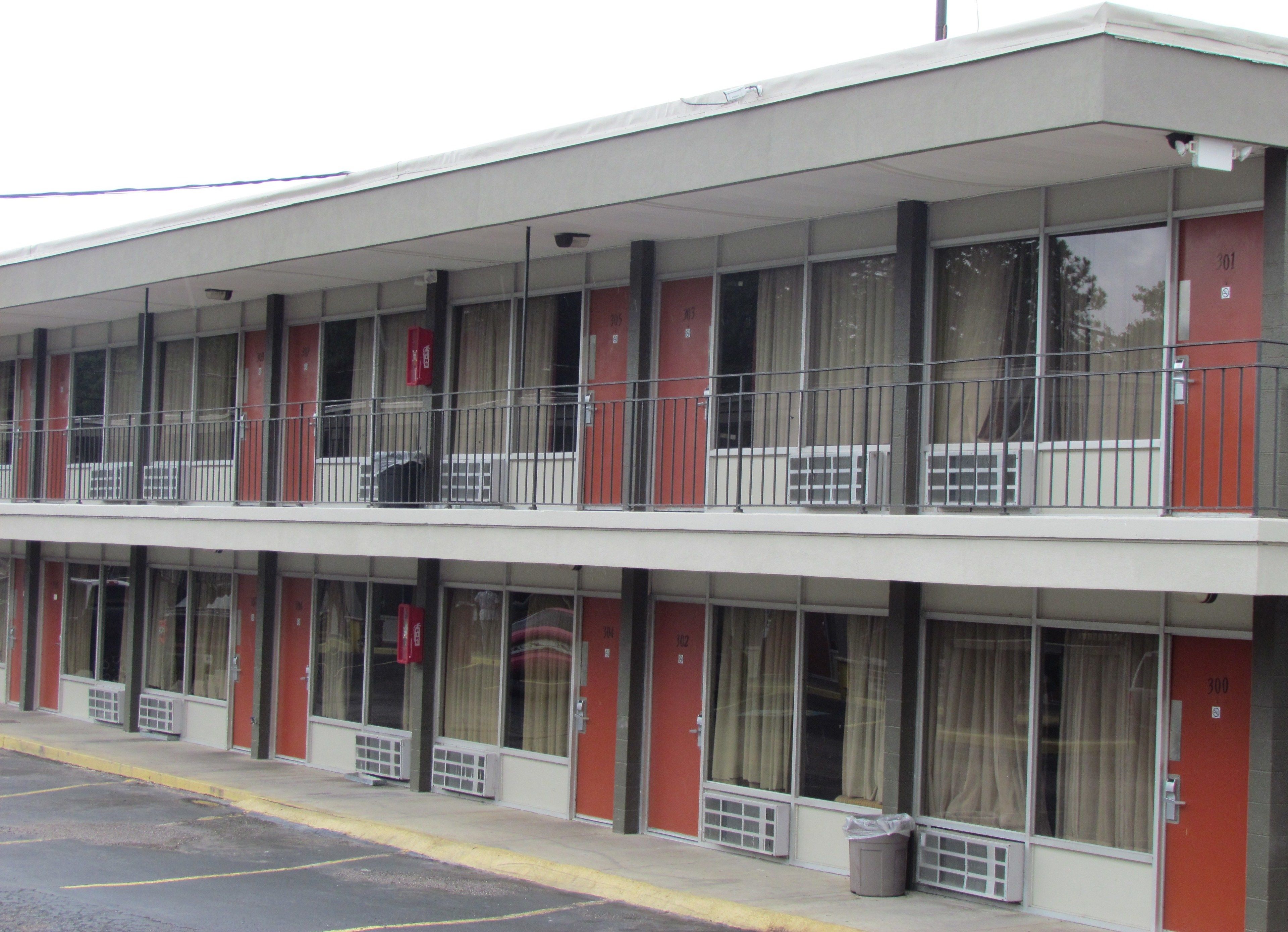Un motel à deux étages, doté d’une façade sobre, de grandes fenêtres et d’une décoration aux couleurs rouge et blanche.