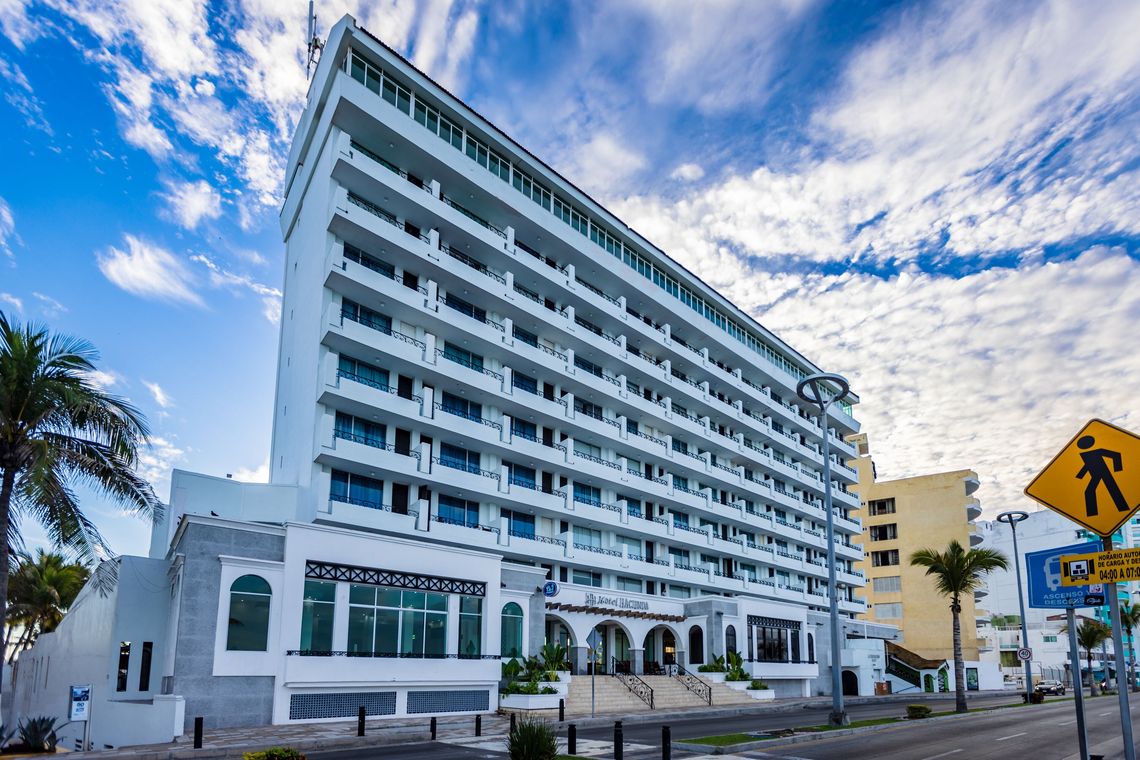 A multi-story hotel with a modern design, featuring balconies, large windows, and a prominent entrance with steps.