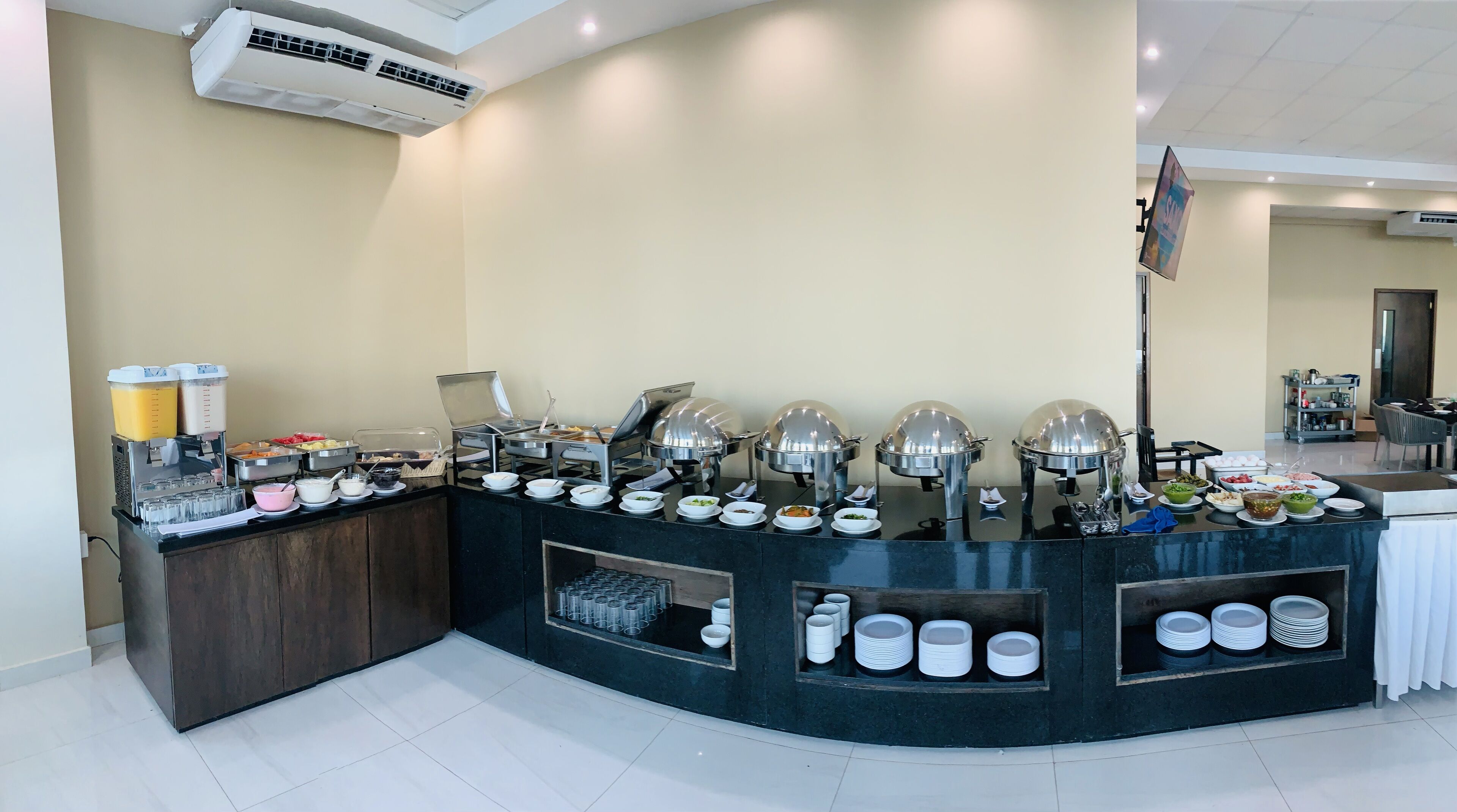 Een buffetopstelling met verschillende gerechten en drankjes, een koffiehoek en een koelkast.