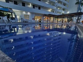 Una piscina al aire libre, sillones reclinables de piscina