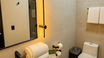 Une salle de bain équipée d’un lavabo, d’un miroir, d’un porte-serviettes, de toilettes et d’une poubelle.