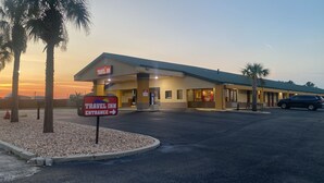 A Travel Inn with a clear entrance sign, a parking lot, and a building with a green roof. - Travel Inn (Unadilla)
