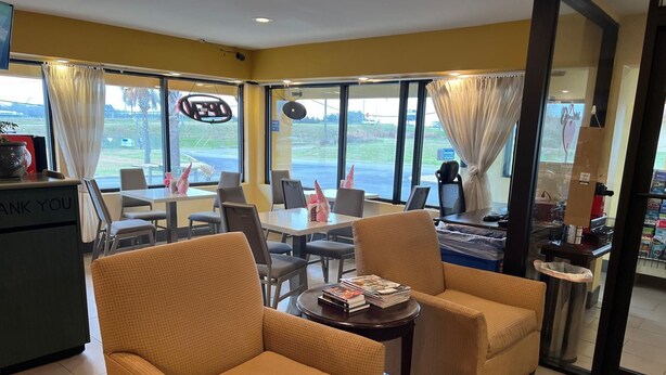 A hotel lobby with a reception desk, seating area, and large windows offering a view of the outdoors. - Travel Inn (Unadilla)