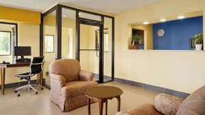 A modern office space with a swivel chair, a desk with a computer, and a small table. - Travel Inn (Unadilla)